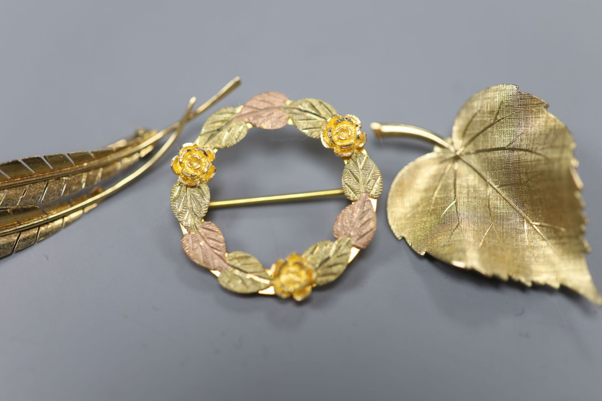 A 585 yellow metal double leaf brooch, 51mm a 9ct gold leaf brooch and a 10k tri-colour foliate wreath brooch (3)